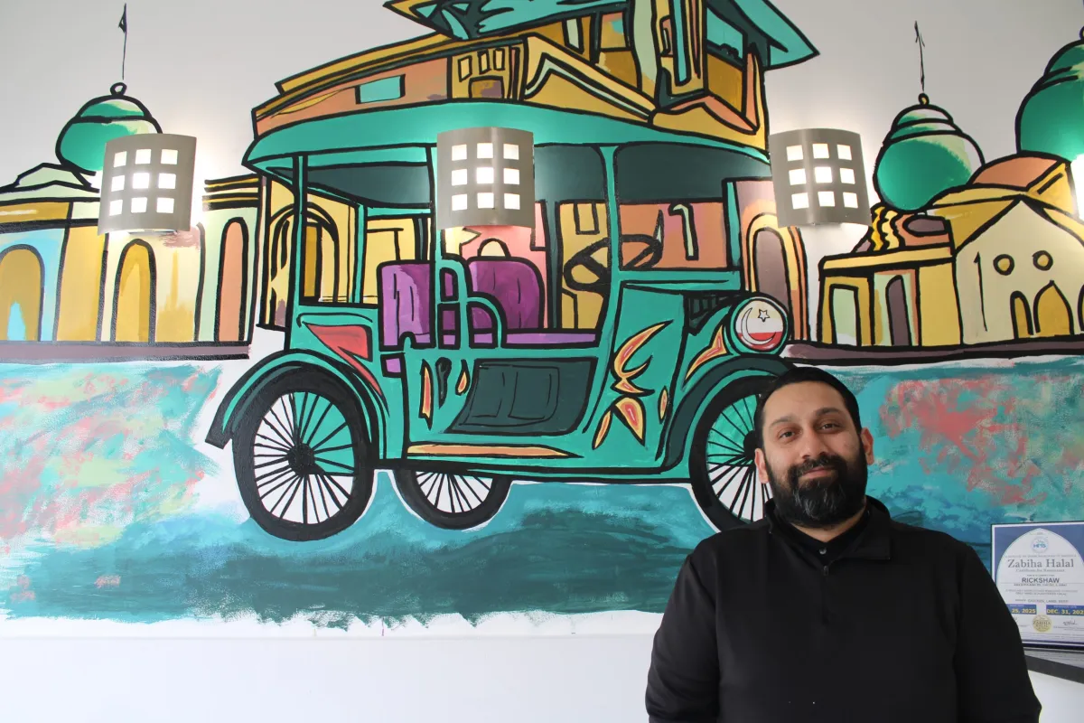 Chef Faraz Sardharia standing inside Rickshaw Pakistani & Indian Street Eats, a Chicago restaurant serving South Asian street food with a focus on community, culture, and giving back.