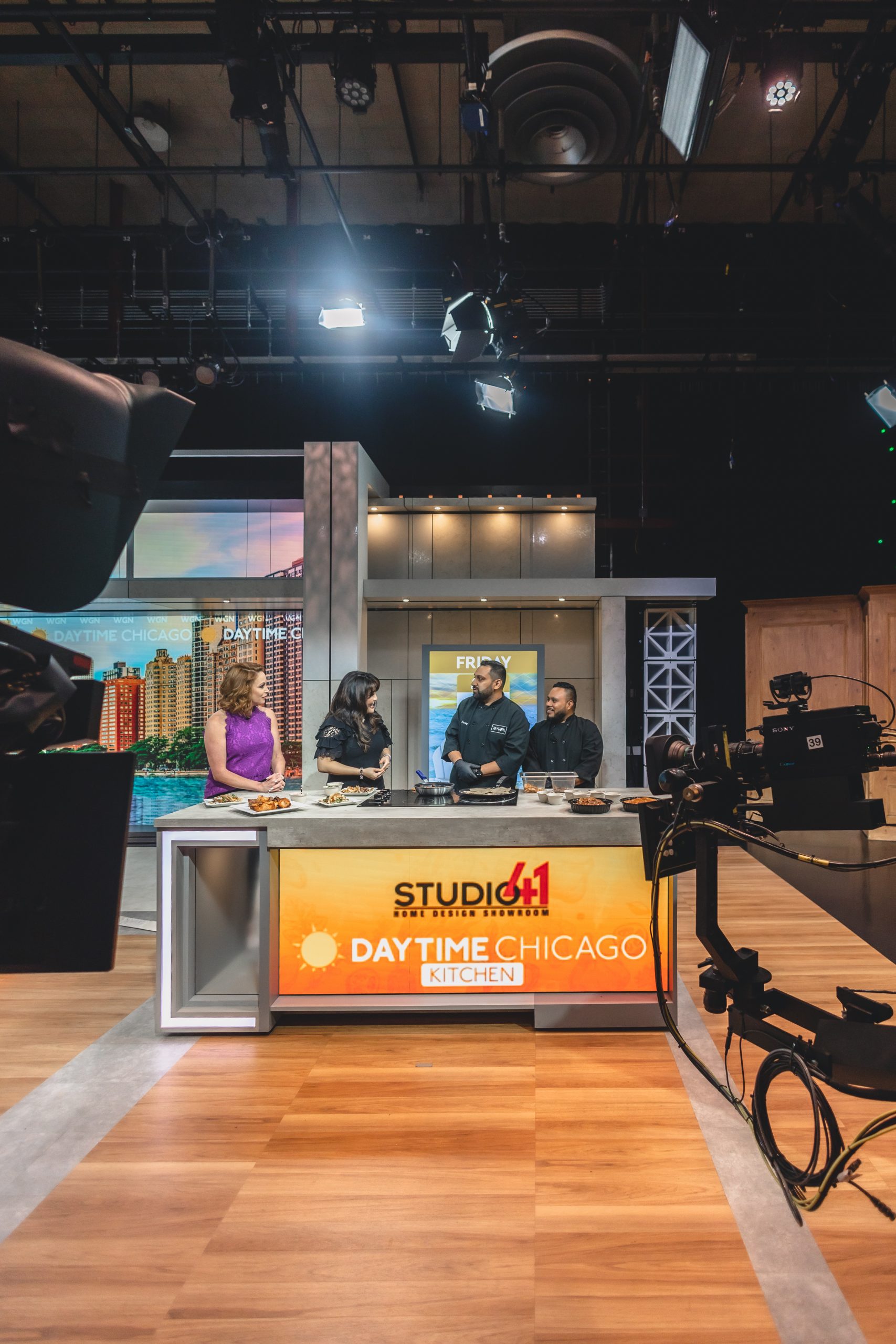 Chef Faraz Sardharia and Chef Augustin standing together presenting plated dishes from Tandoor Char House during a cooking segment on Daytime Chicago.
